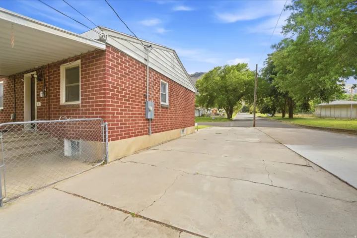 Brick exterior with white trim, covered patio, and concrete driveway
