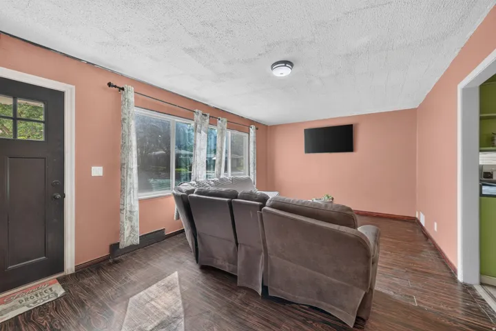 Dark wood-finish flooring, multiple windows, and a dark paneled entry door with transom