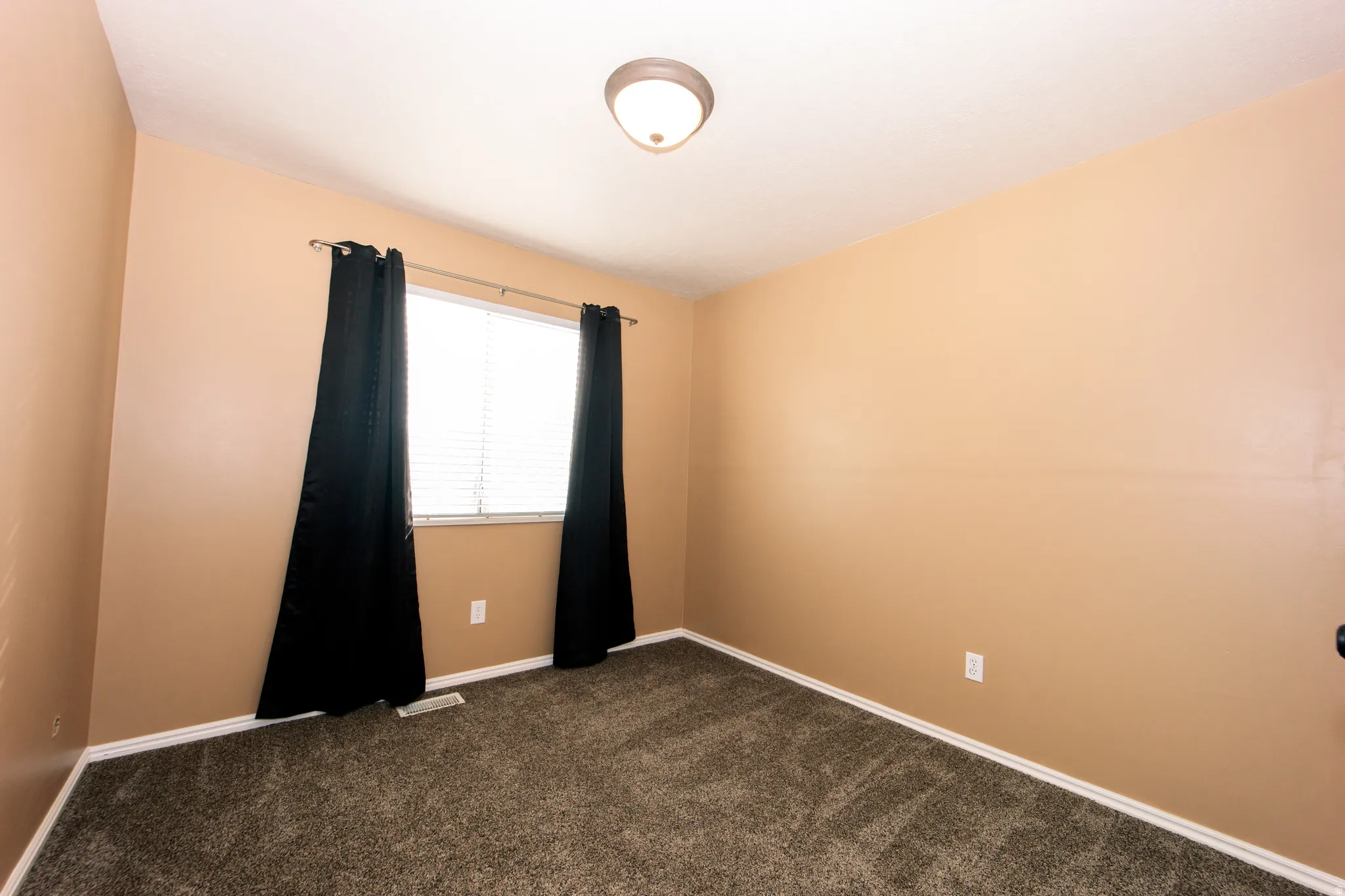 Neutral-toned walls complement the window with blinds, providing natural light to the carpeted floor