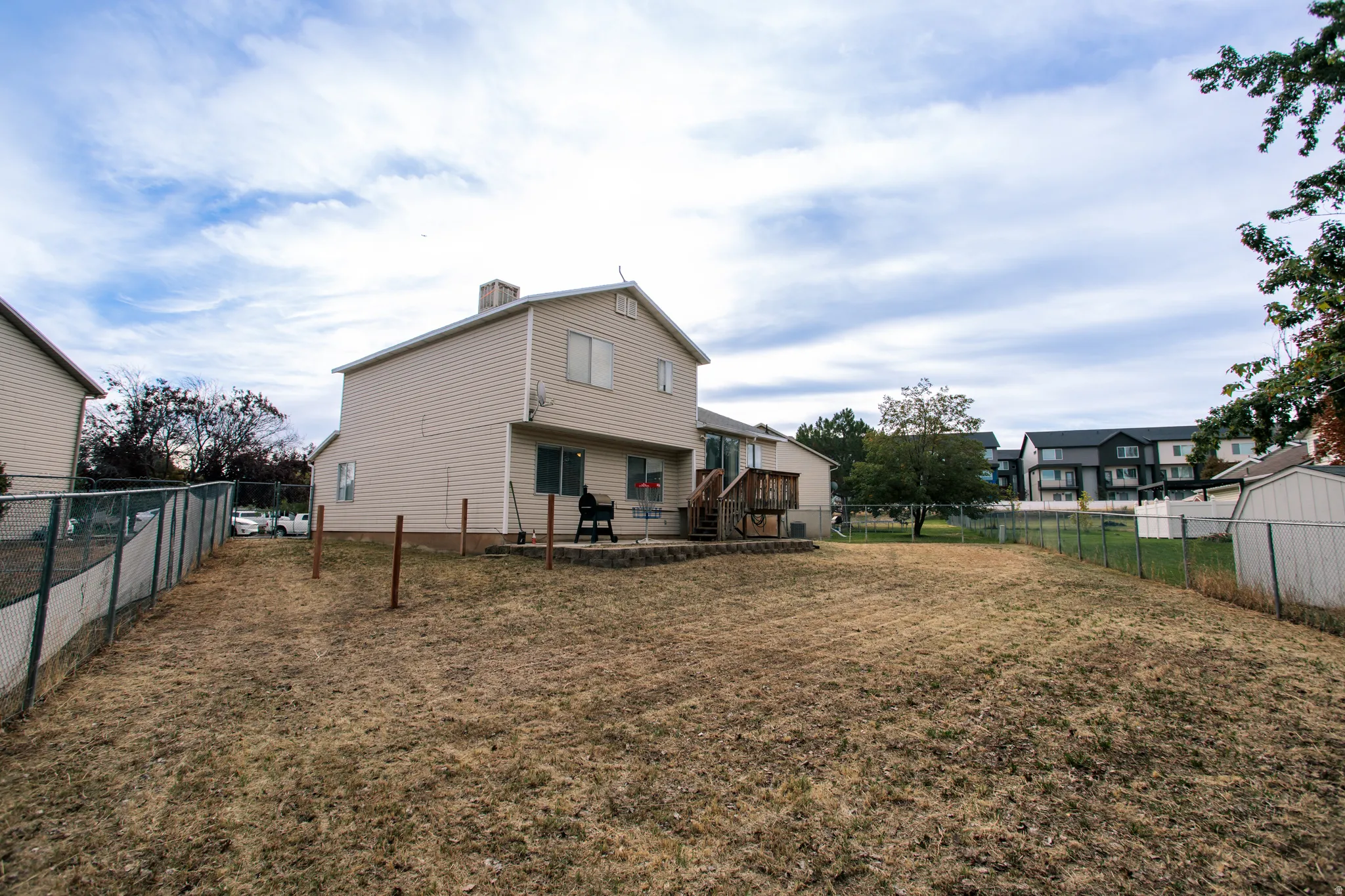 Expansive rear yard with chain link fencing and a wood deck