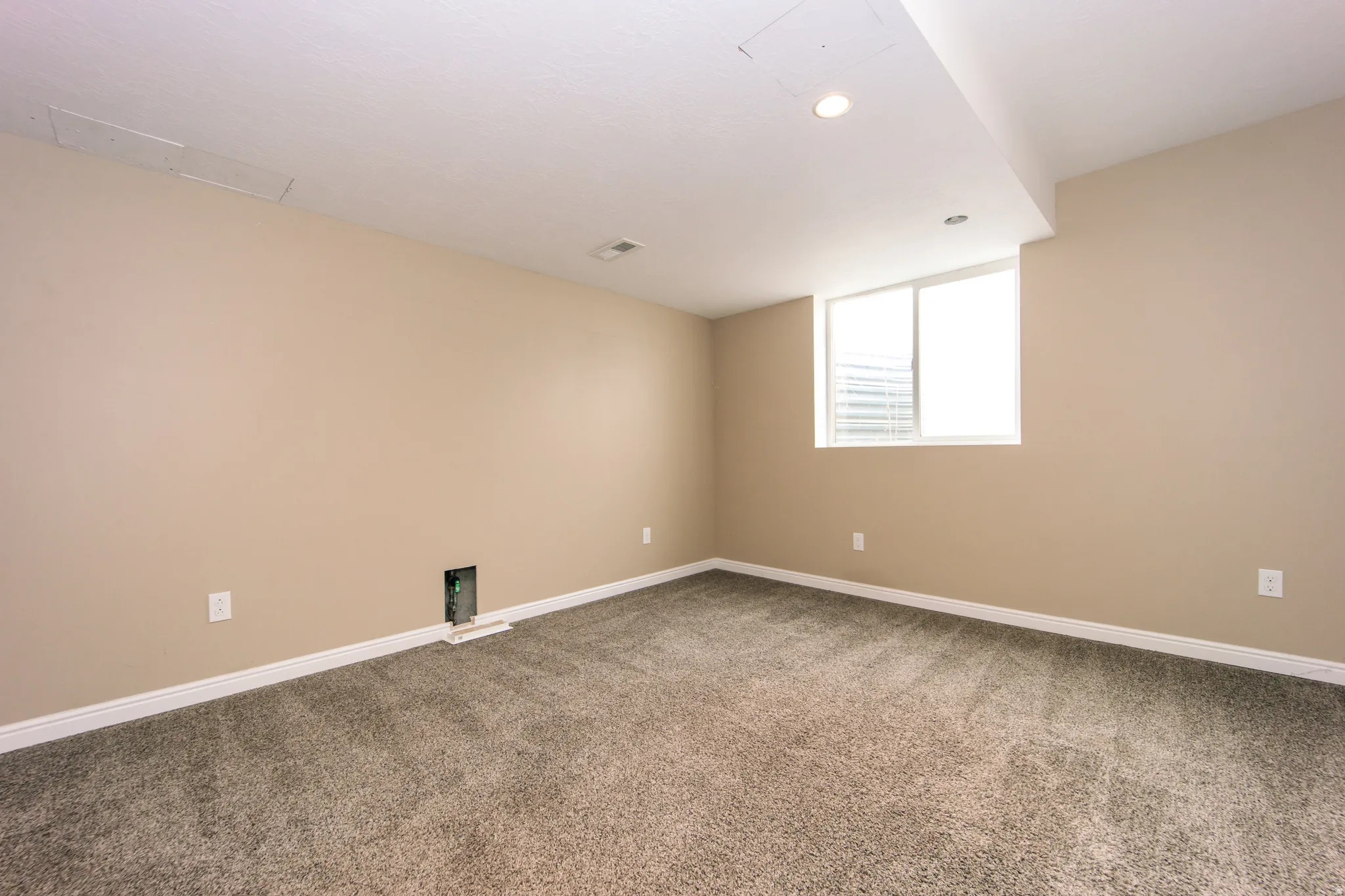 Recessed ceiling lighting, neutral carpet, egress window, white trim, and light-toned wall paint