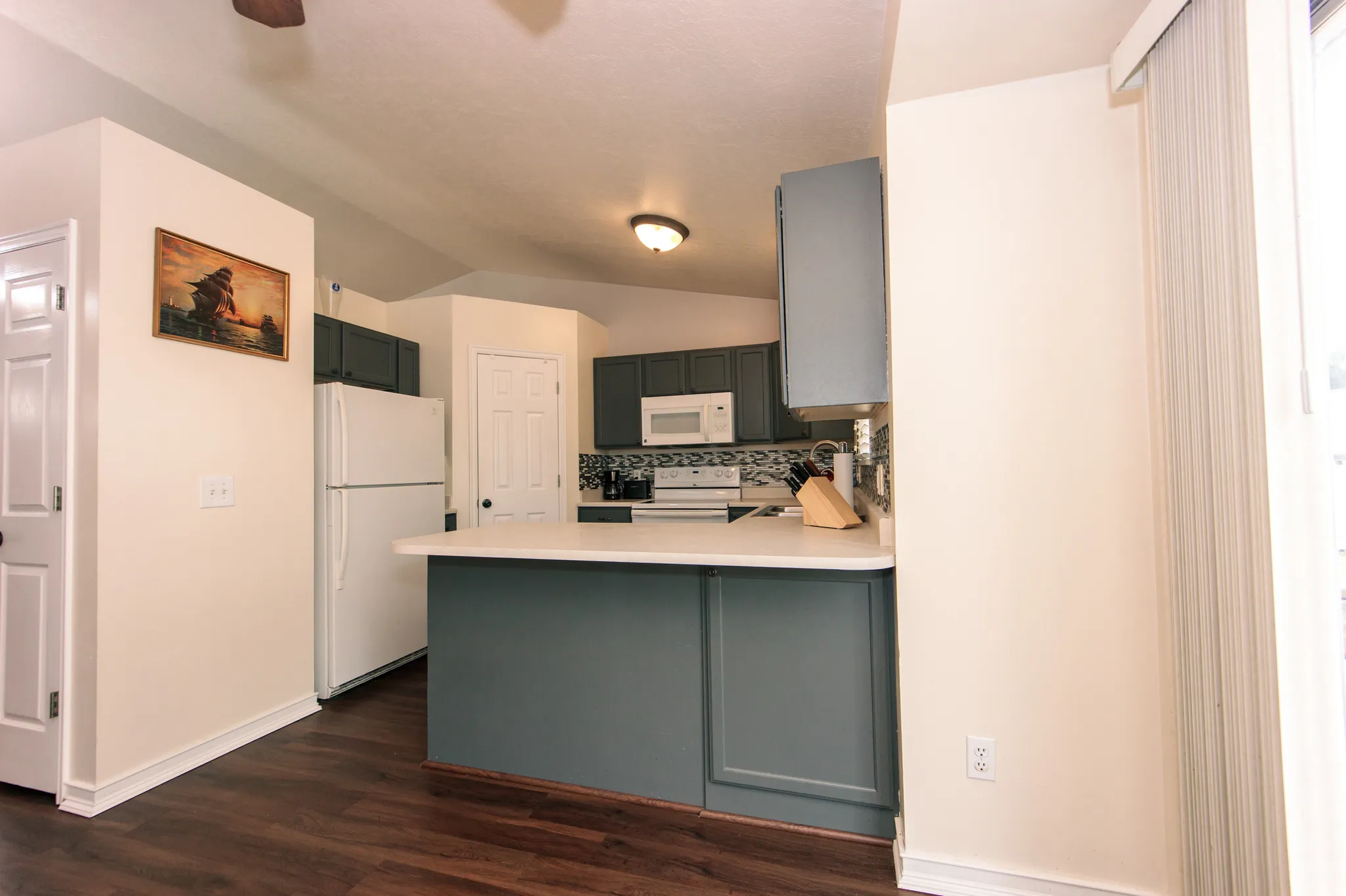 Kitchen featuring wood-finish flooring, white appliances, gray cabinetry, white countertops, and a decorative tile backsplash