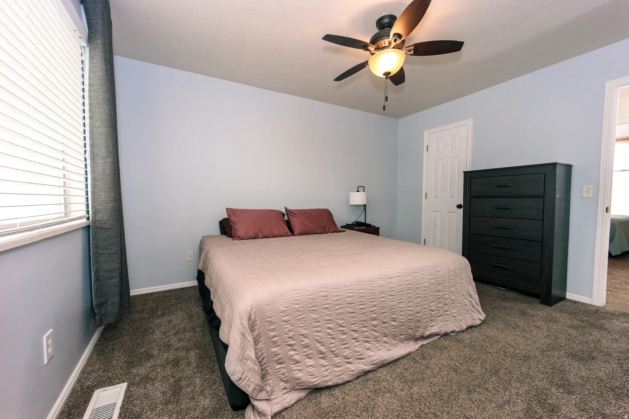 Plush carpeting and a window with blinds provide comfort