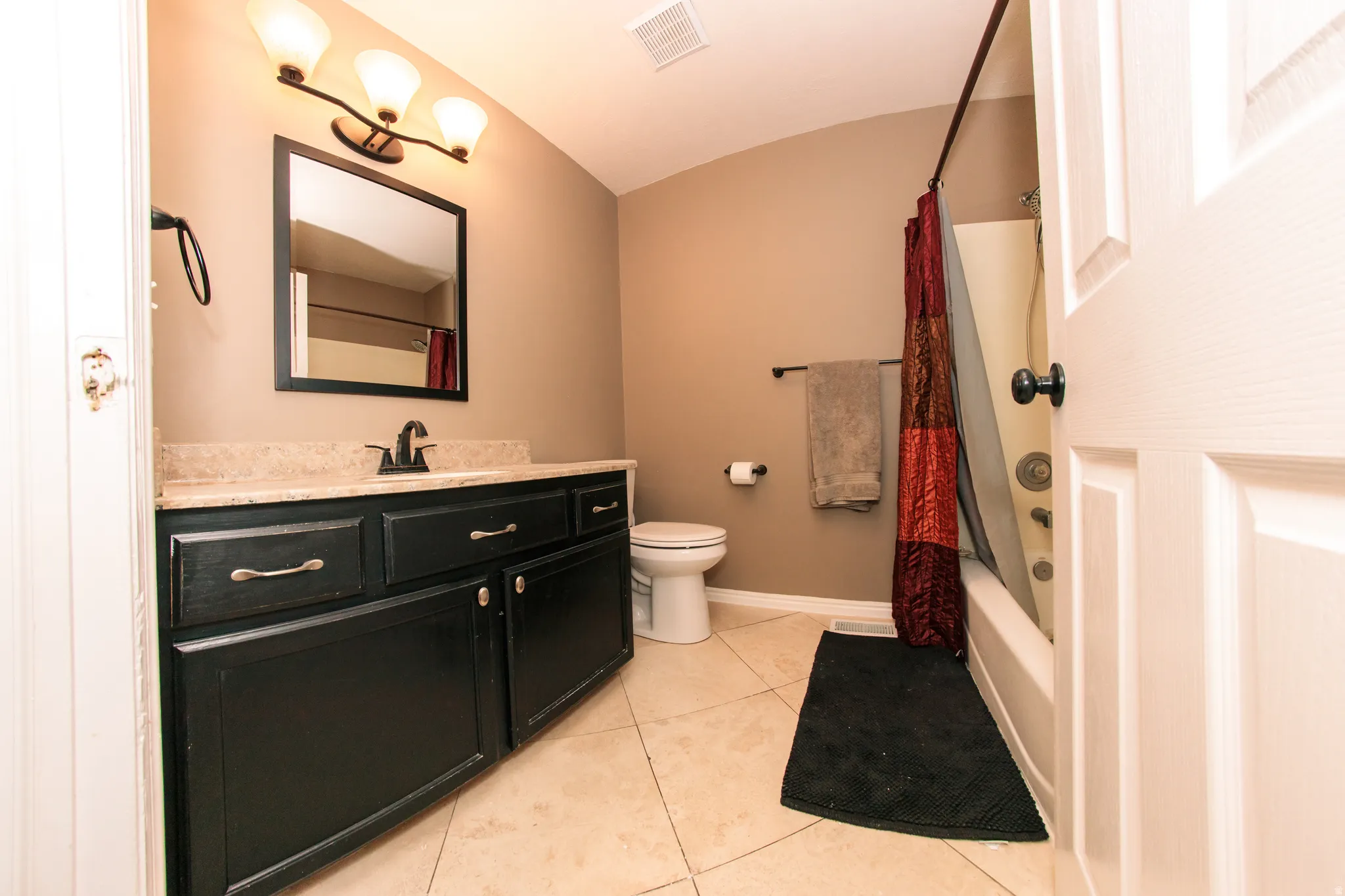 Black vanity with brushed nickel hardware, stone-finish countertop, and integrated sink