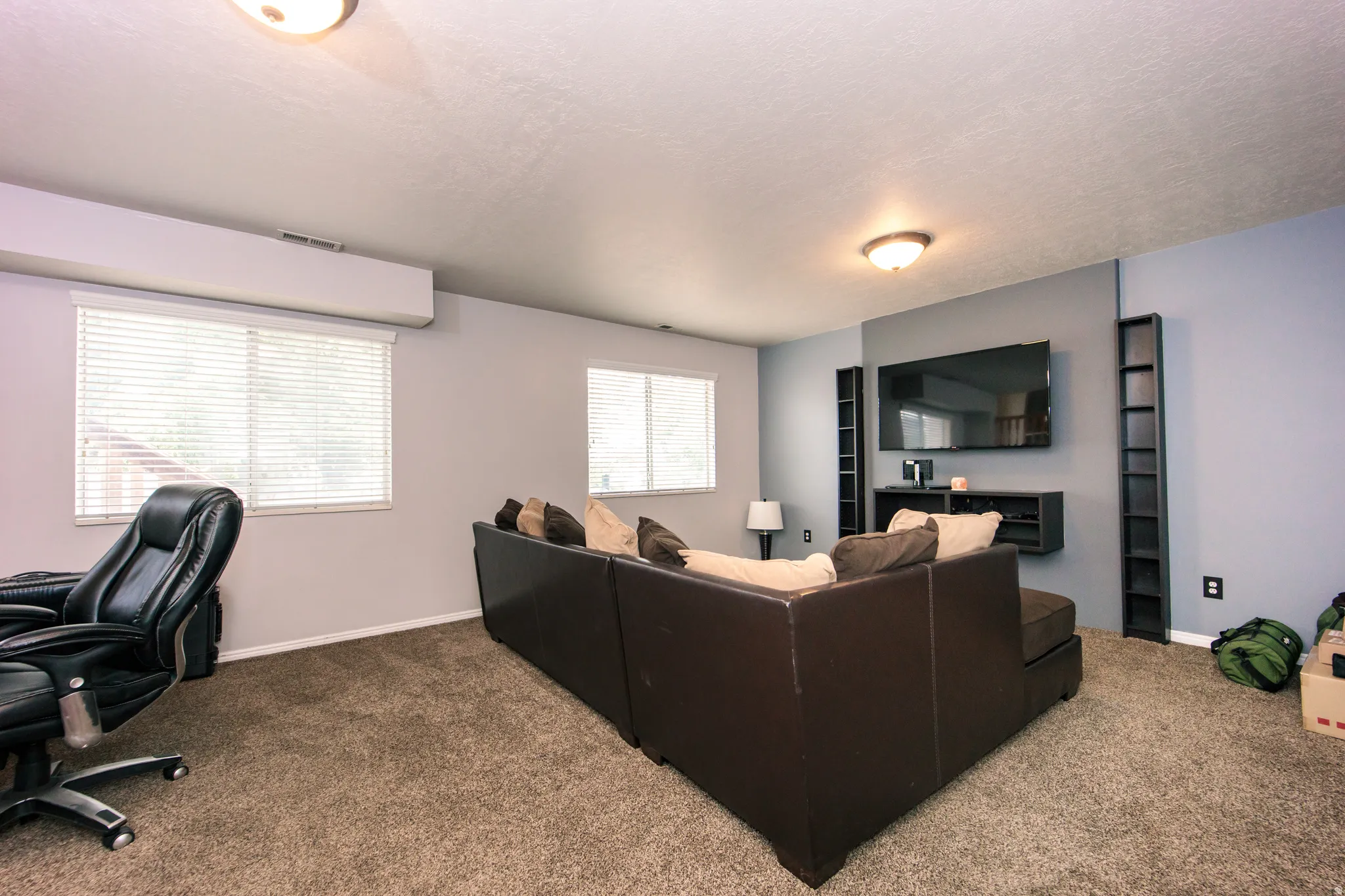 Recessed lighting with a textured ceiling, two windows featuring blinds, and carpeted flooring