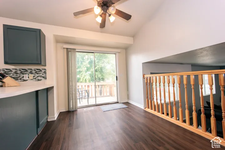 Wood-finish flooring, vaulted ceiling, sliding glass door to exterior deck, wood balustrade, and contemporary cabinetry