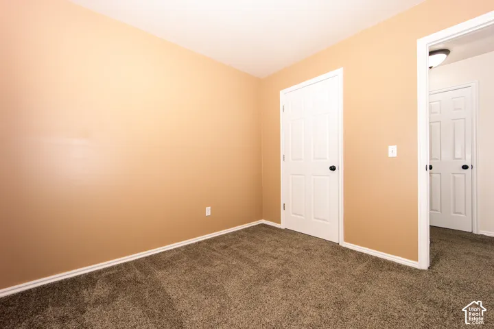 Neutral wall paint, plush carpet flooring, white trim, and white paneled doors