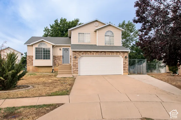 Two-story residence featuring a brick and siding exterior, an attached garage, a paved driveway, and a front entry door with exterior steps