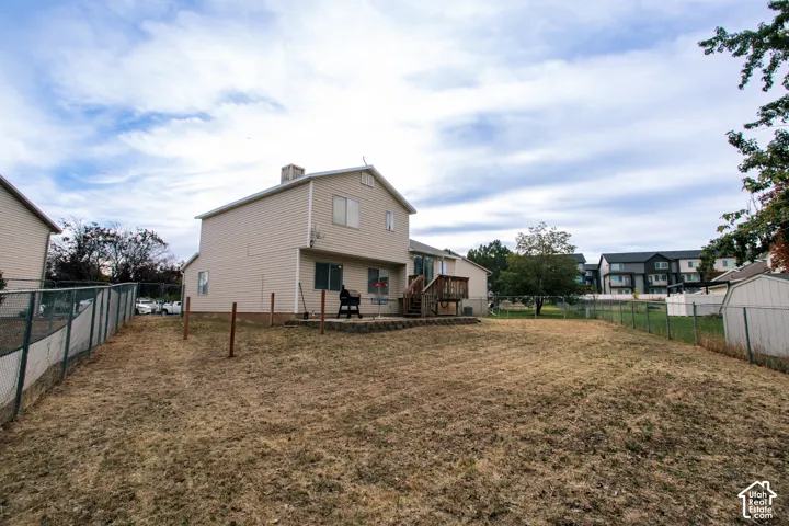 Expansive rear yard with chain link fencing and a wood deck