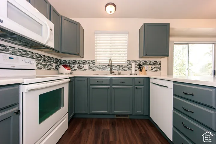 Kitchen featuring dark gray cabinetry, white countertops, a mosaic tile backsplash, wood-finish flooring, and a sliding glass door