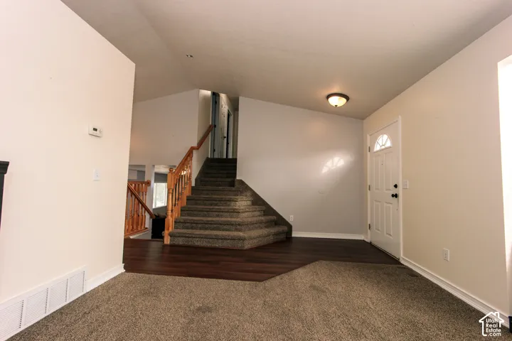 Carpeted flooring, wood-finish flooring, staircase with wood railing, recessed entry, and wall-mounted lighting