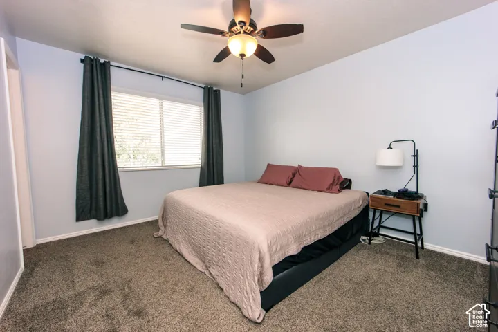 Carpeted room featuring a ceiling fan with light fixture, a window with horizontal blinds, and light blue walls