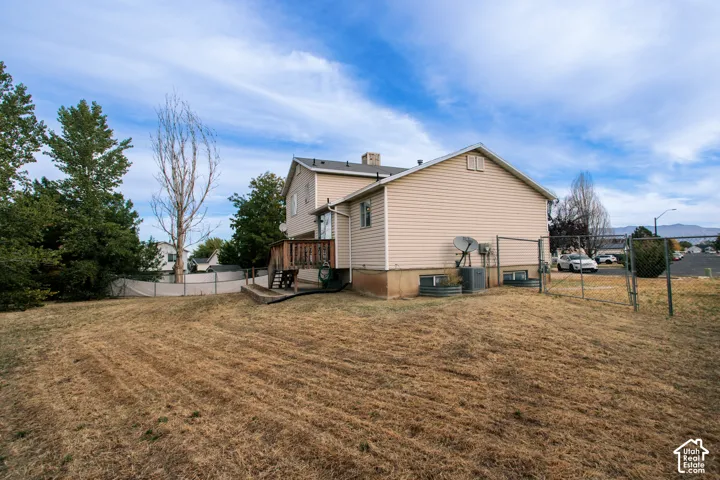 Expansive backyard featuring a chain-link fence, a multi-level wood deck, and mature trees