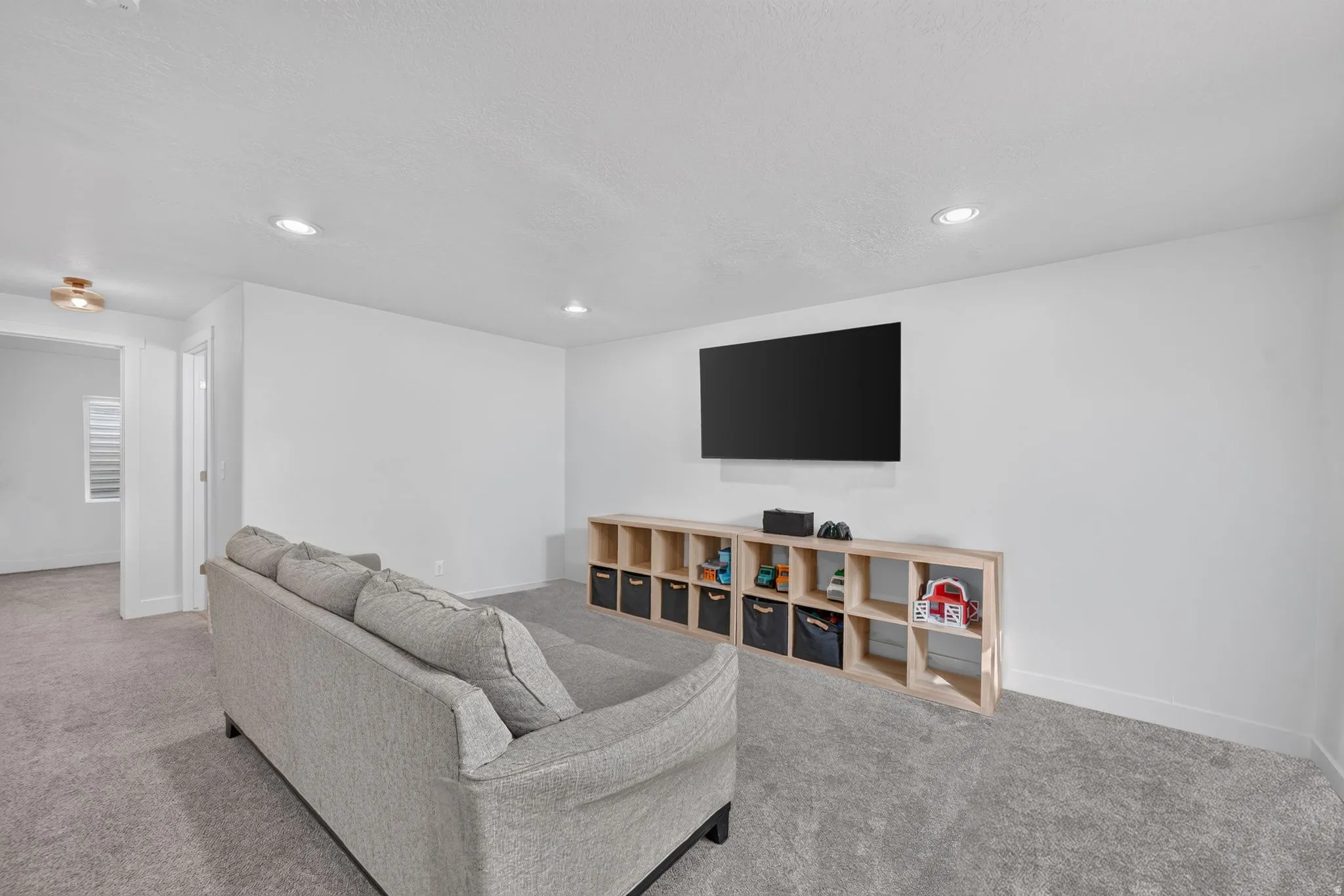 Recessed lighting, light-toned carpeting, and a built-in wall-mounted television
