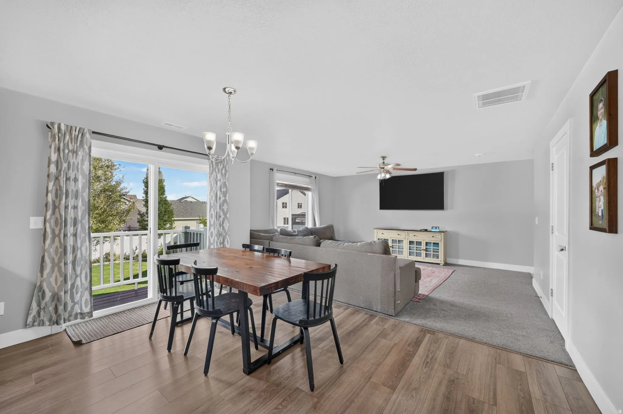Wood-finish flooring, sliding glass door to outdoor deck, recessed lighting, ceiling fan, and chandelier