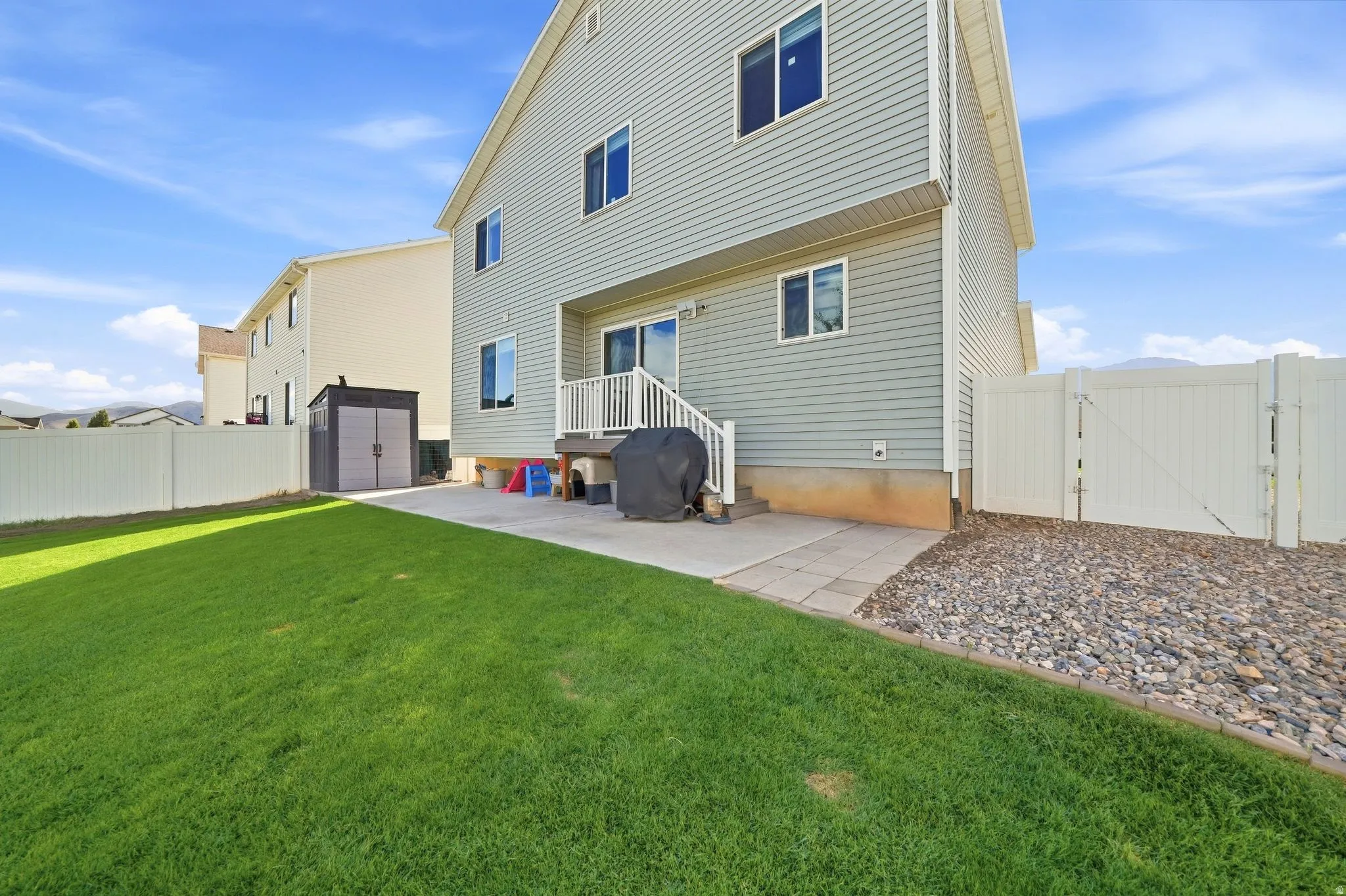 Expansive lawn with a paver patio and rock landscaping