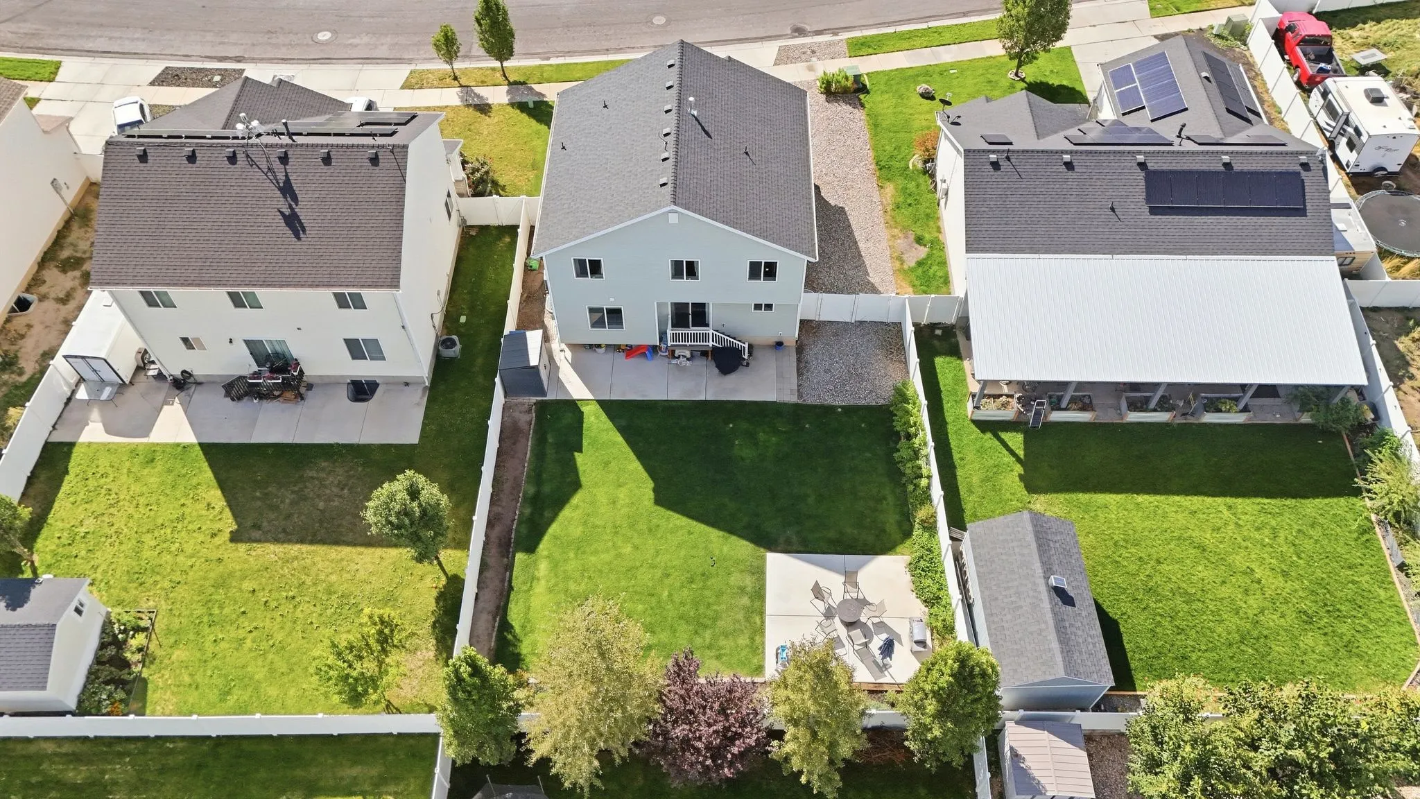 Expansive backyard featuring a manicured lawn, concrete patio, and mature trees