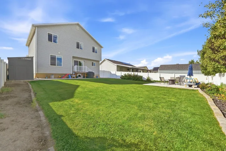 Expansive backyard featuring a lush lawn, concrete patio, and privacy fencing