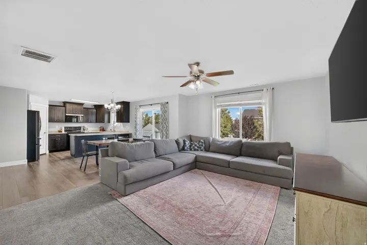 Open-concept living space featuring wood-finish flooring, a ceiling fan, and large windows