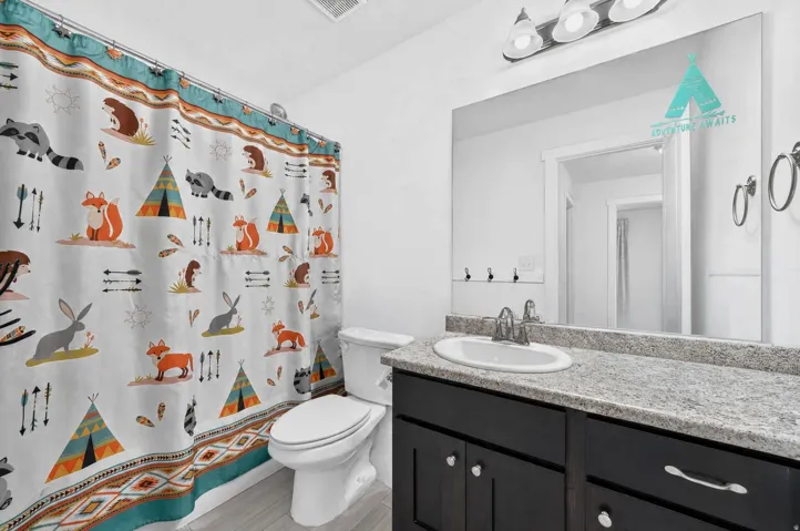 Granite-finish countertop with an integrated sink, dark wood-finish vanity with drawer pulls, and a wall-mounted mirror