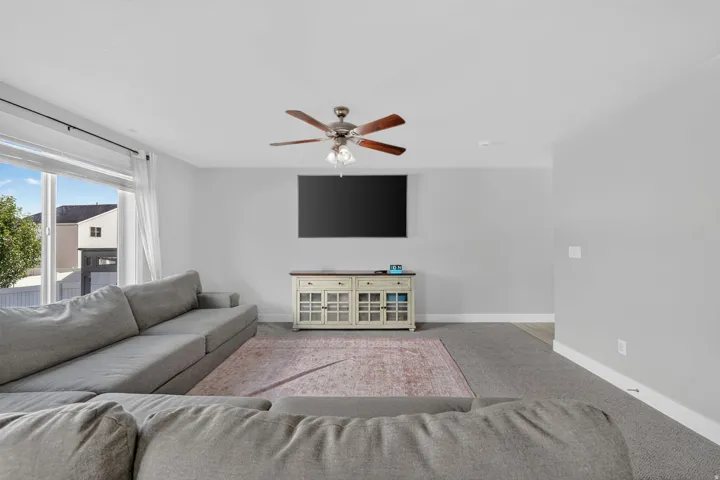Large picture window, ceiling fan, recessed lighting, wall-mounted television, and a built-in media console