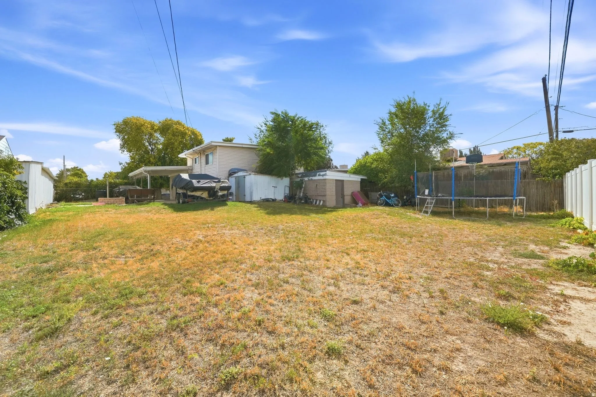 Expansive outdoor area featuring a partial privacy fence and detached storage sheds