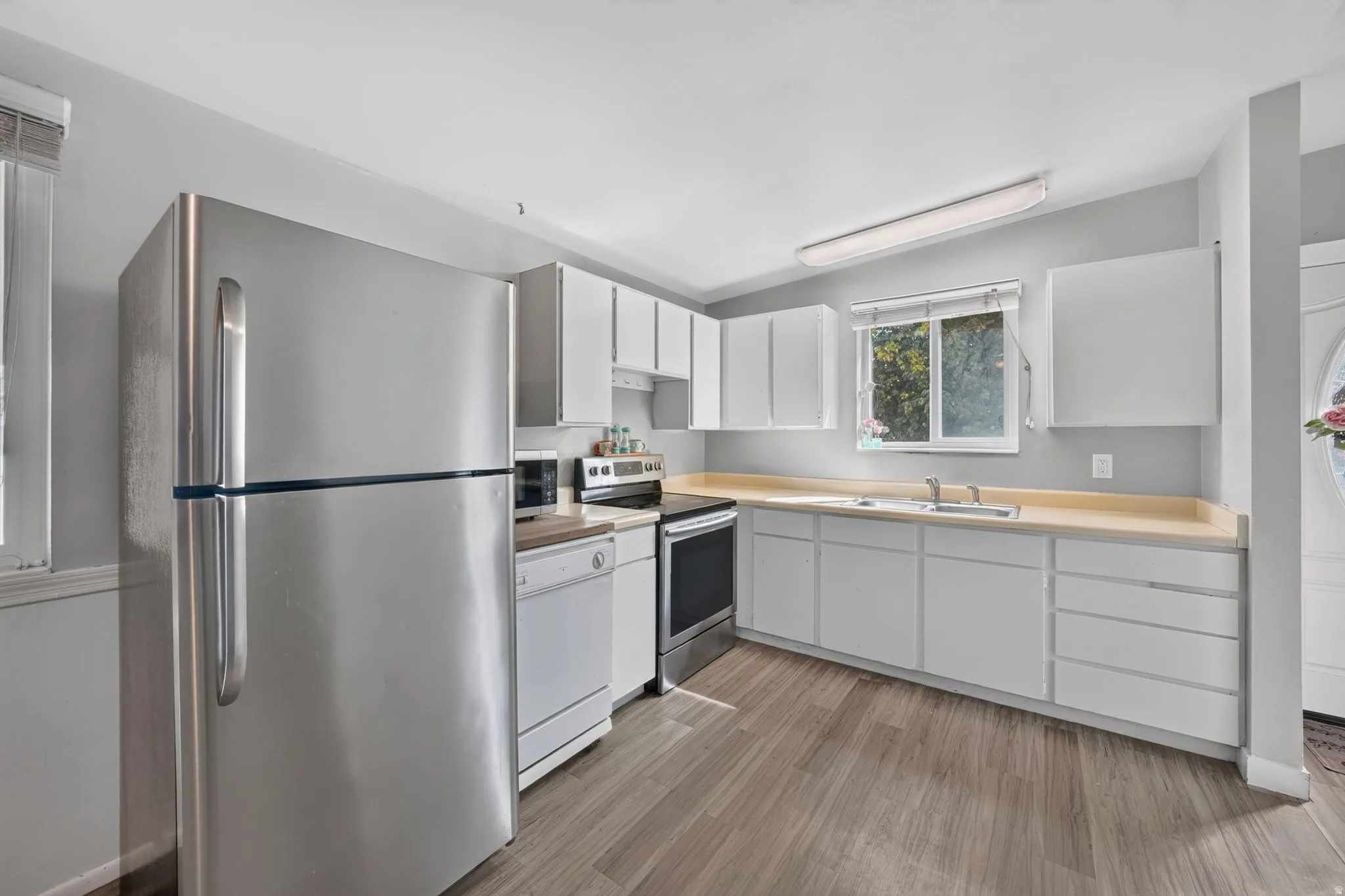 Kitchen featuring wood-finish flooring, white cabinetry, laminate countertops, and stainless steel appliances