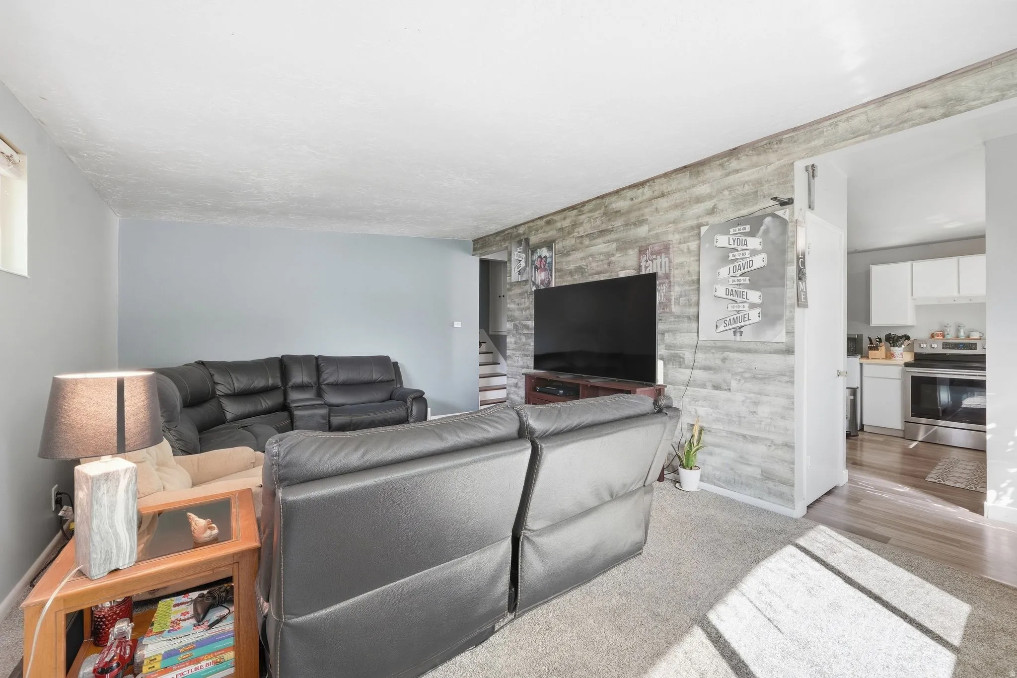 Living area with a wood-finish accent wall, light gray wall paint, and carpet flooring