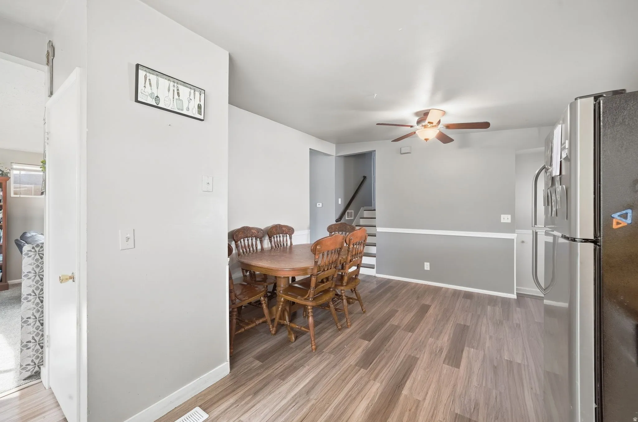 Wood-finish flooring, two-tone wall paint, and a ceiling fan with integrated lighting
