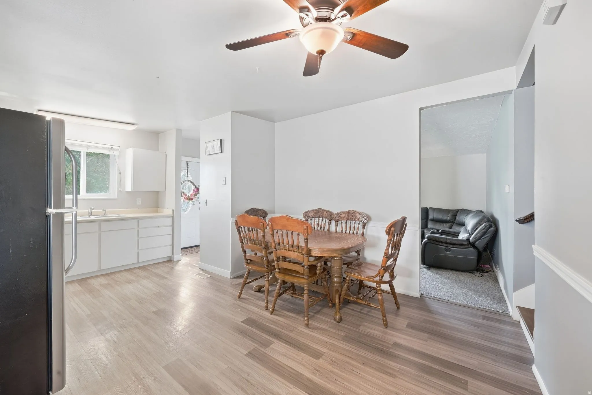 Kitchen area with light wood-finish flooring, white cabinetry, and a stainless steel sink
