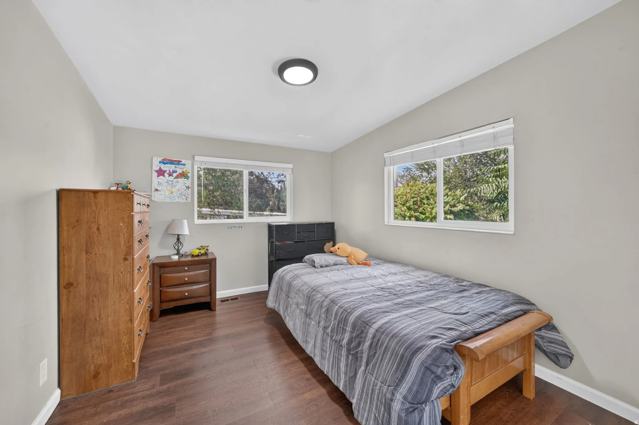 Wood-finish flooring throughout, light gray wall paint, and dual windows with white blinds