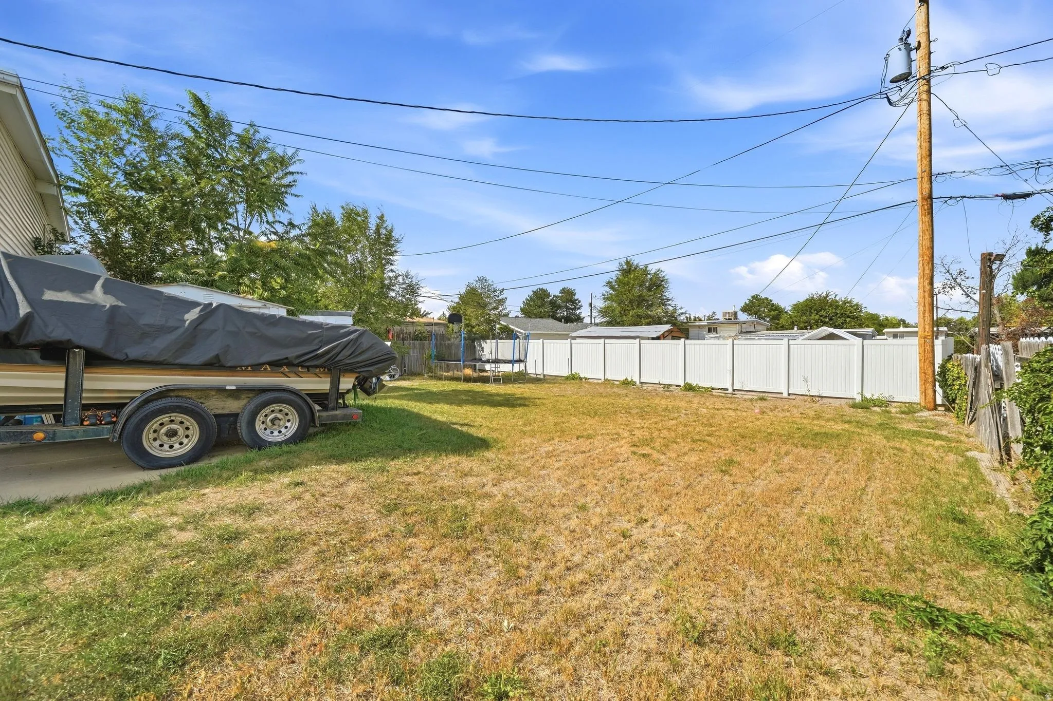 Expansive grass area with a white privacy fence