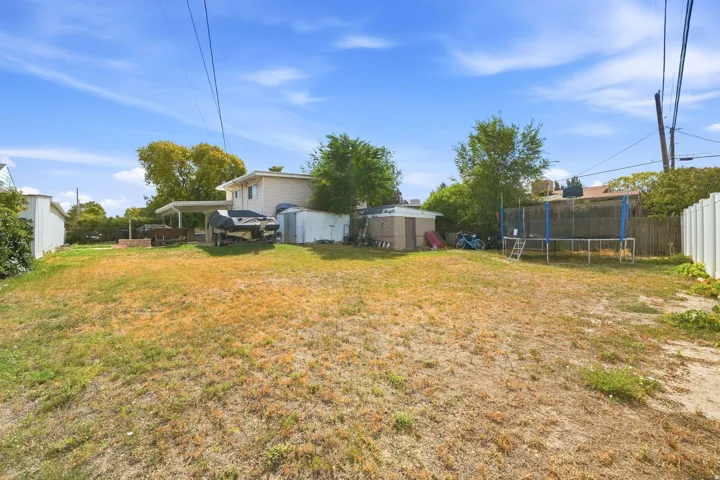 Expansive outdoor area featuring a partial privacy fence and detached storage sheds