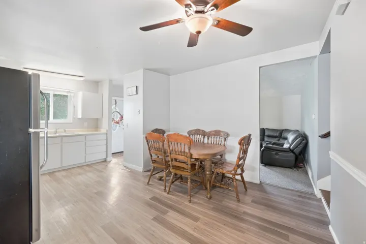 Kitchen area with light wood-finish flooring, white cabinetry, and a stainless steel sink