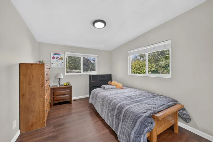 Wood-finish flooring throughout, light gray wall paint, and dual windows with white blinds