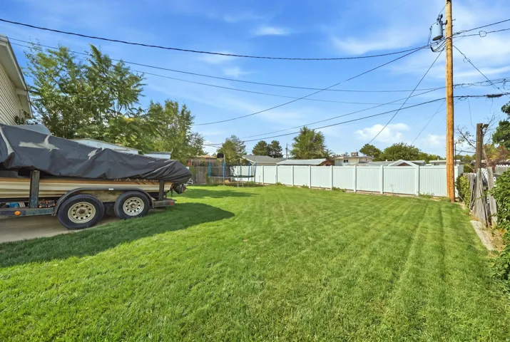 Expansive grassy yard with white privacy fencing and a paved side yard
