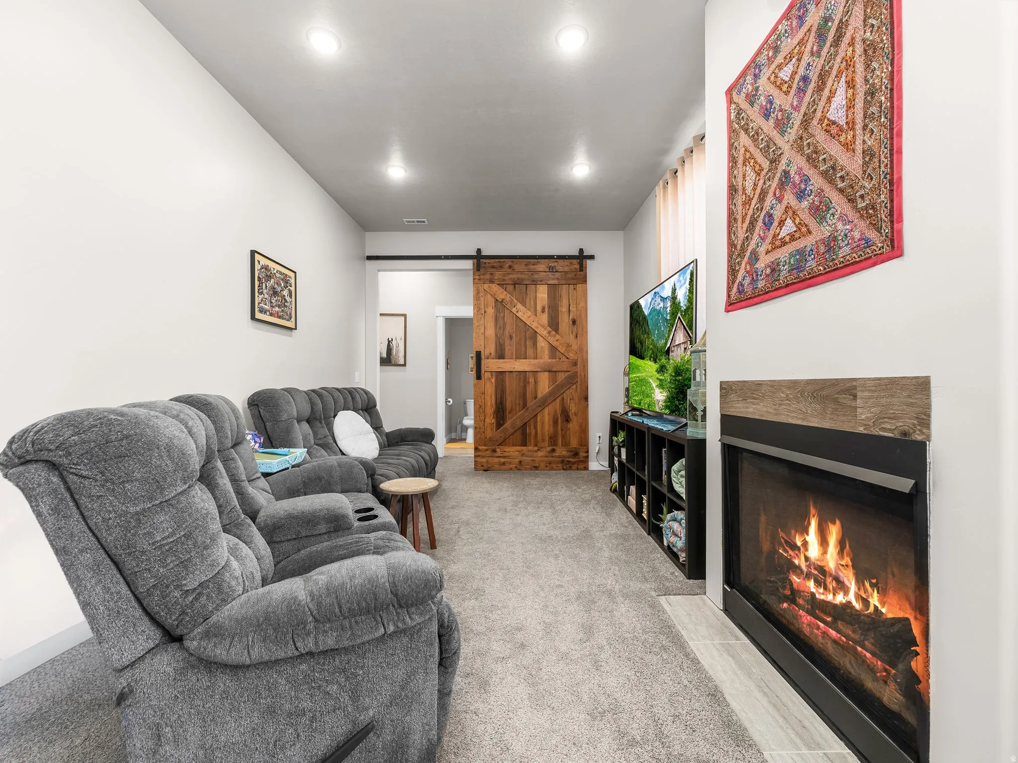 Recessed ceiling lighting, carpeted flooring, built-in fireplace, and a wood-finish barn door