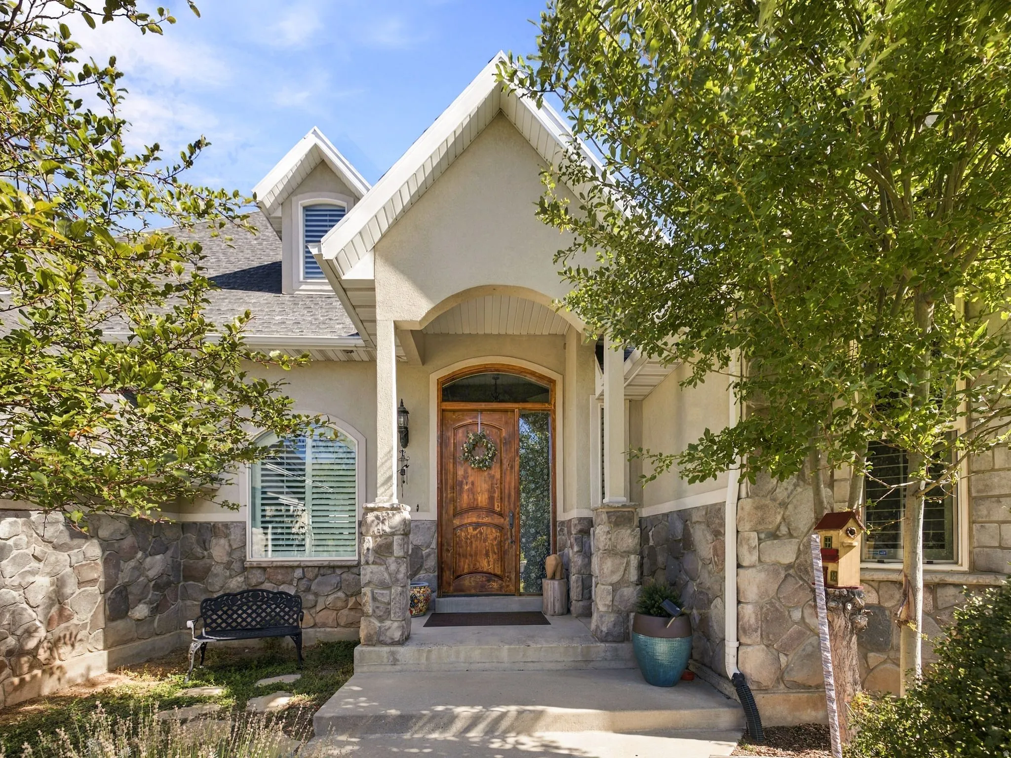 Stucco and stone exterior with an arched entryway, dormer window, and a wood-paneled front door
