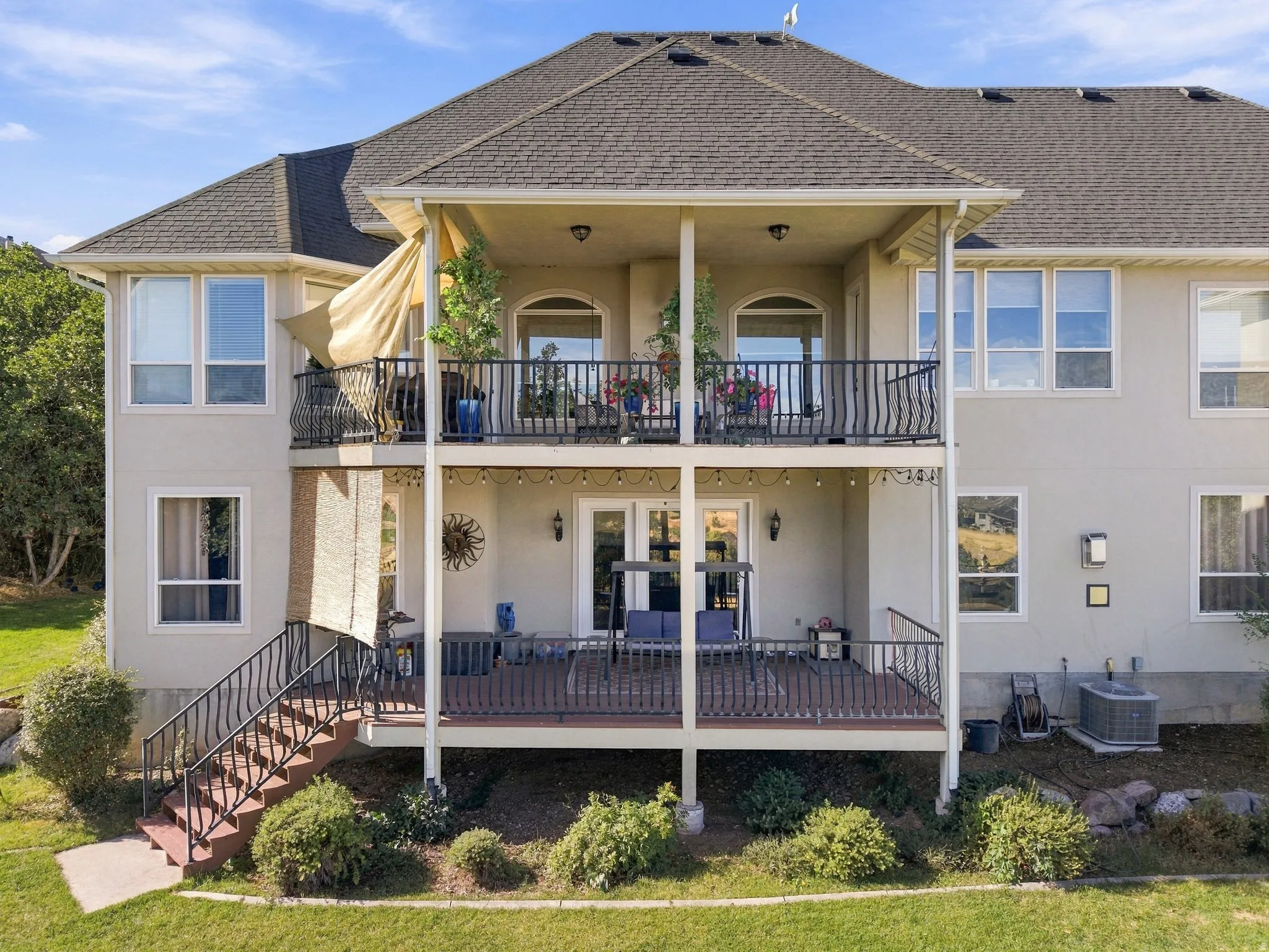 Stucco exterior with a multi-level deck, dark wood railing, and an asphalt shingle roof