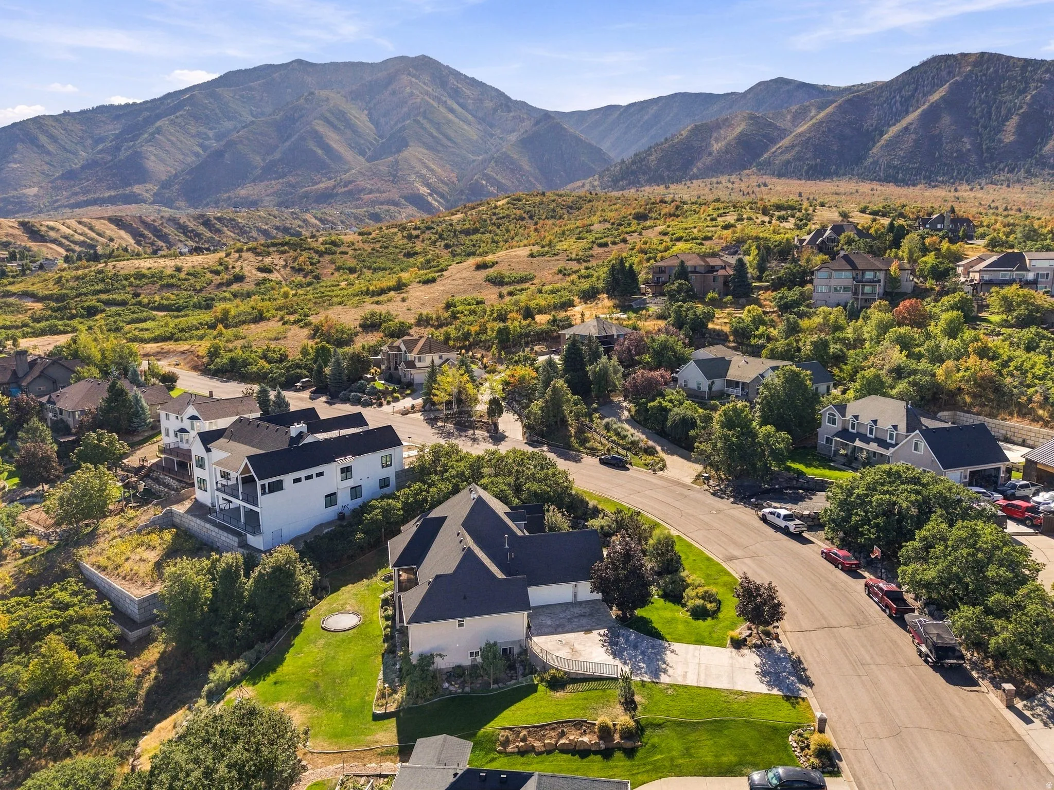 Mountainous backdrop, residential neighborhood setting, paved streets, varied architectural styles, mature trees and landscaping