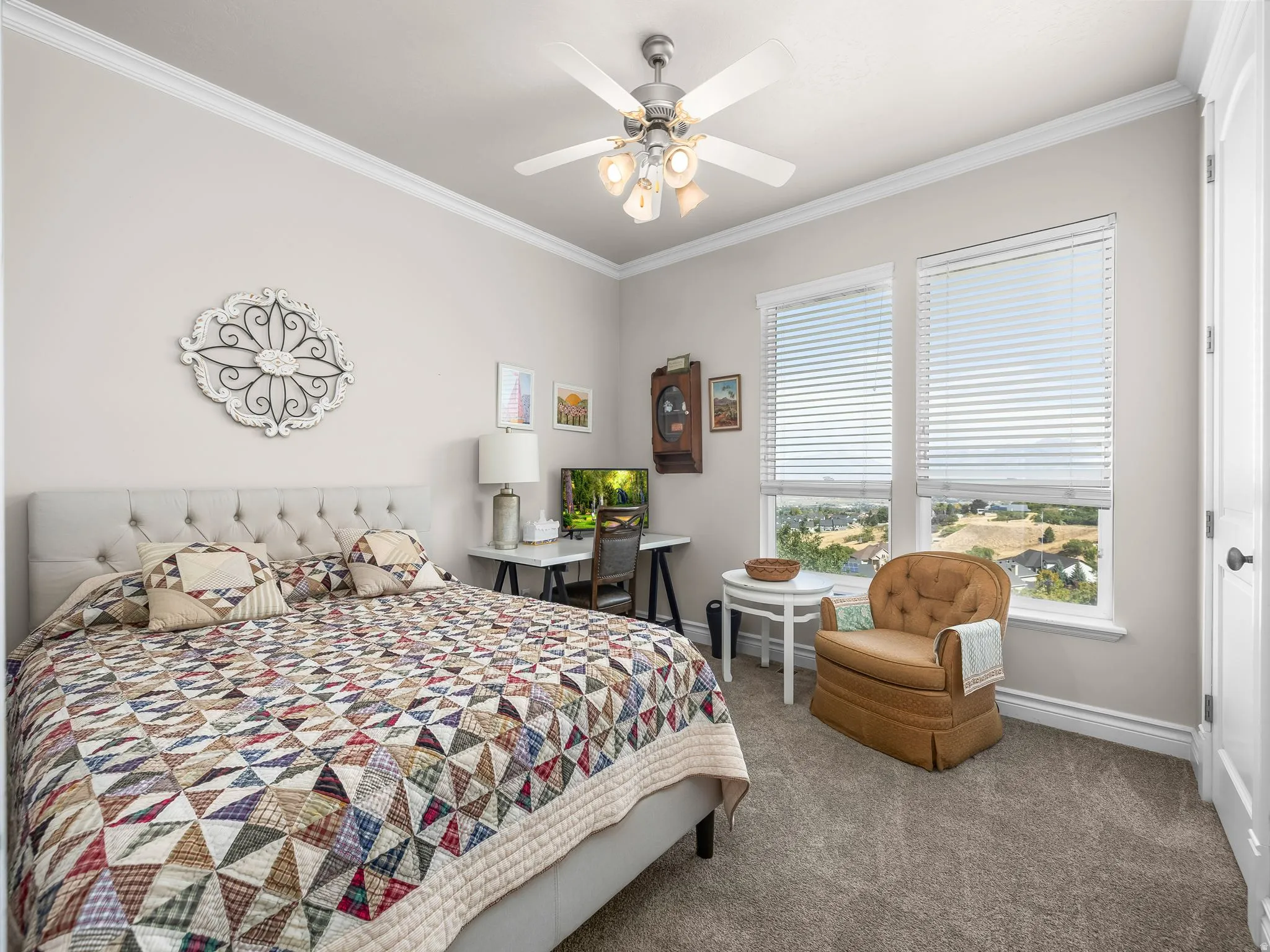 Wall-to-wall carpeting, crown molding, two large windows with blinds, a ceiling fan with light fixture, and a paneled door