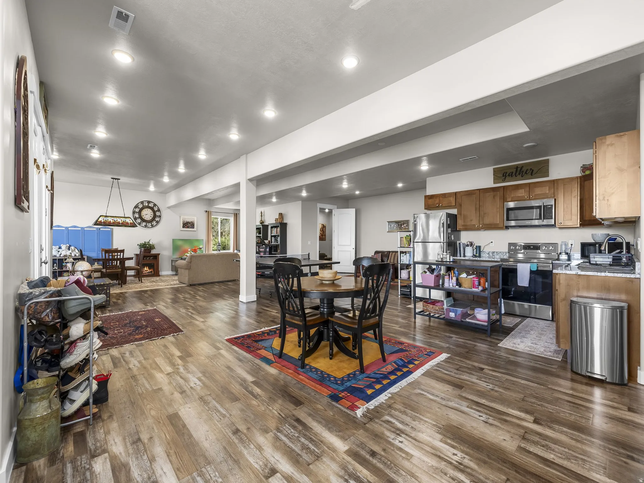 Expansive open-concept living area featuring wood-finish flooring, recessed lighting, and a kitchen with wood cabinetry and stainless steel appliances