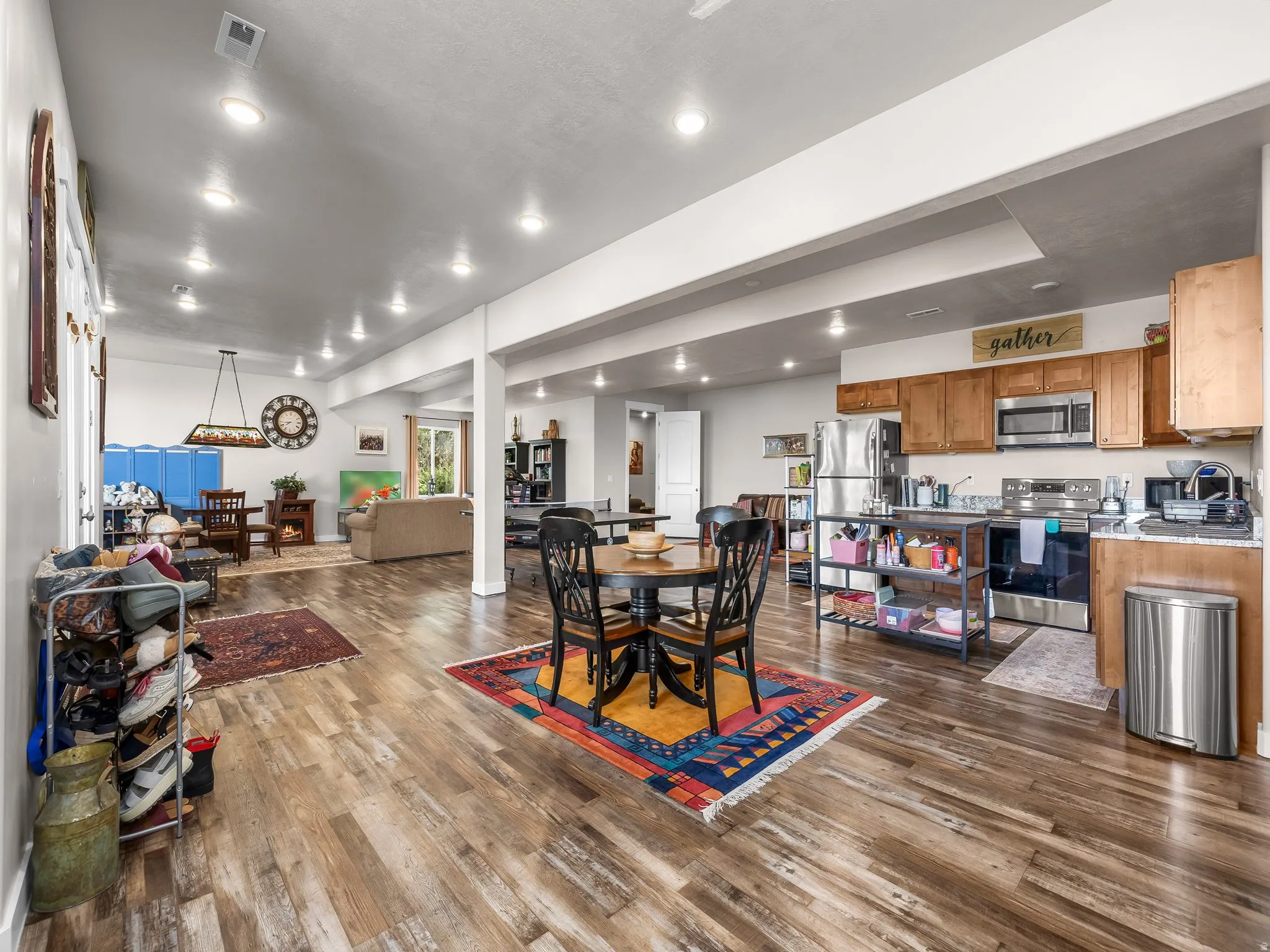 Open-concept living area featuring wood-finish flooring, recessed lighting, a full kitchen with stainless steel appliances, and wood cabinetry
