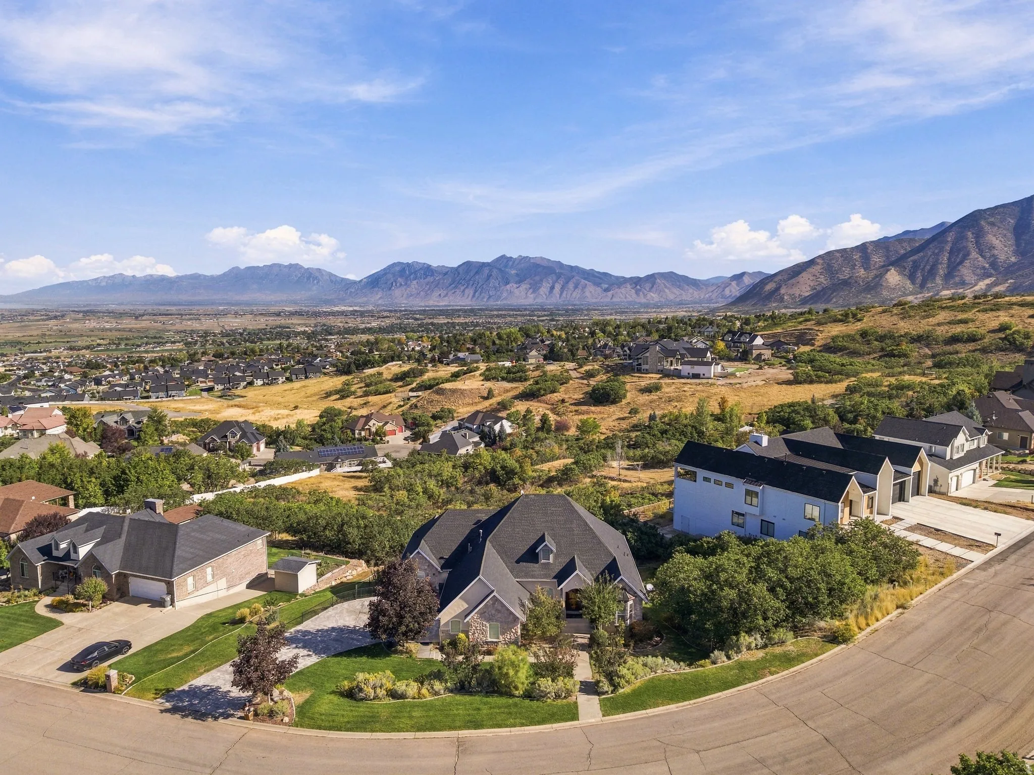 Expansive mountain backdrop, residential neighborhood setting, well-maintained landscaping, paved street, and diverse architectural styles