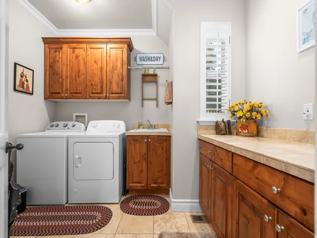 Laundry room featuring wood cabinetry, a utility sink, a built-in countertop, and tile flooring