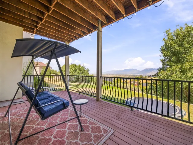 Expansive outdoor deck with wood-finish flooring, black wrought-iron railings, and mountain scenery