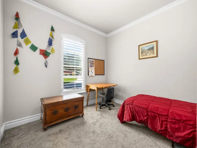 Arched window with plantation shutters, crown molding, white baseboards, and neutral wall color
