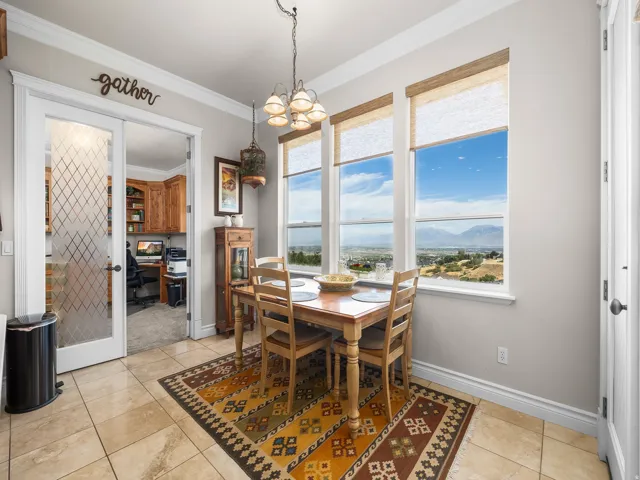 Floor-to-ceiling windows, tile flooring, glass-paneled double doors, crown molding, and a built-in office with wood cabinetry