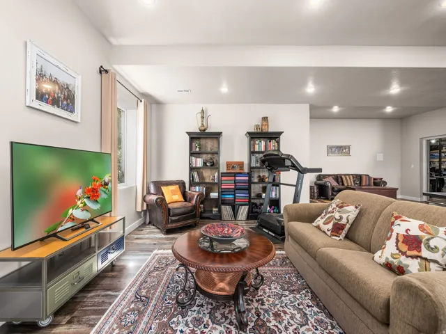 Spacious living area featuring recessed lighting, a window with drapery, and wood-finish flooring
