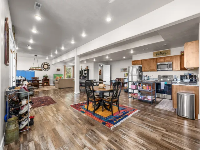 Open-concept living area featuring wood-finish flooring, recessed lighting, a full kitchen with stainless steel appliances, and wood cabinetry